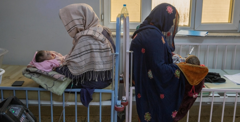 Zwei Frauen sitzen mit ihren Babys auf dem Schoss auf Betten