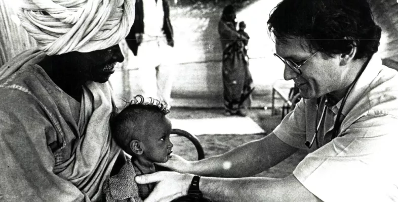 Dr. Rony Brauman behandelt ein Kind Schwarz-weiß-Foto von Arzt der Kind behandelt
