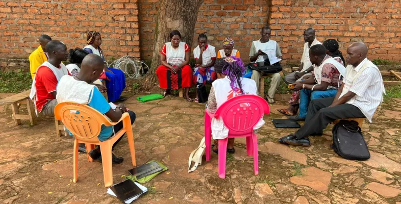 Mitarbeitende sitzen draußen in Kreis bei Besprechung
