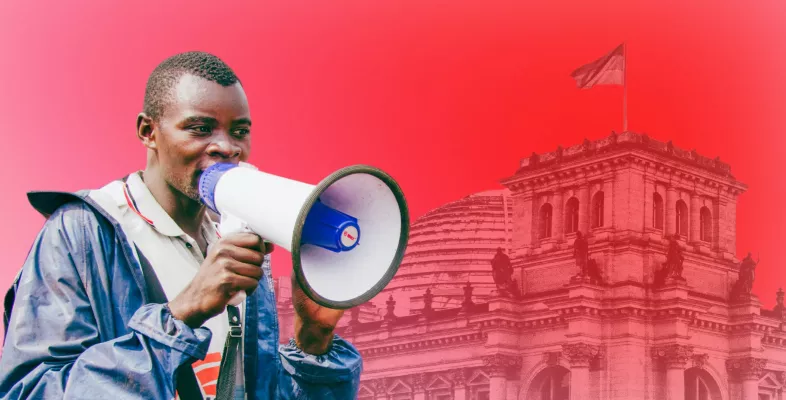 Mitarbeitender mit Megaphon vor rotem Hintergrund mit Bundestag