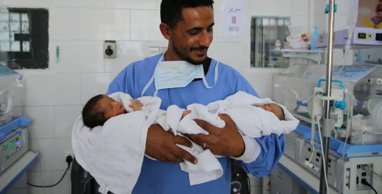 Foto eines Vaters, der seine beiden Zwillinge im Arm hält