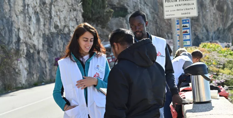 Mitarbeitende sprechen mit Geflüchteten auf Weg