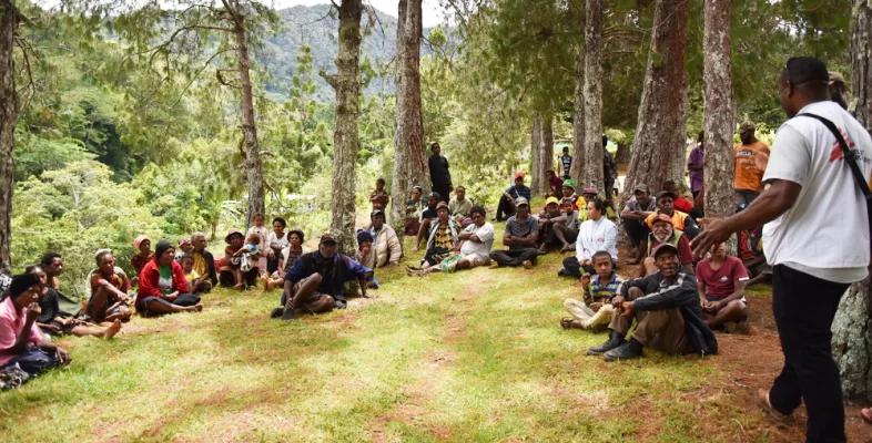Mitarbeitender spricht zu Gruppe Sitzender in Wald