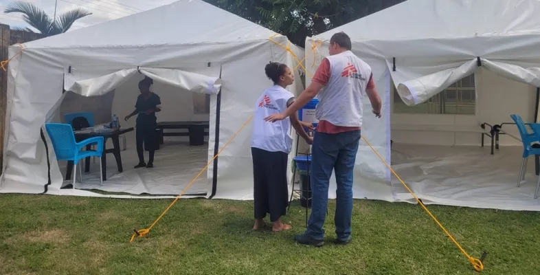 Zwei Mitarbeitende vor Behandlungszelten