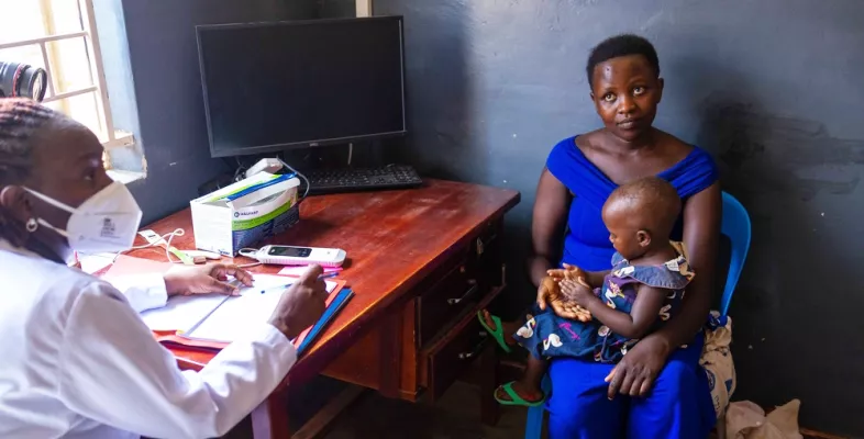 Frau mit Kind auf Schoß in Gespräch mit Mitarbeitender