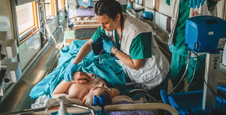 Zwei Mitarbeitende arbeiten an Bett von Patient in Zug