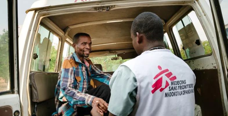 Ein Mitarbeiter hilft einem Patienten an Bord eines Krankenwagens