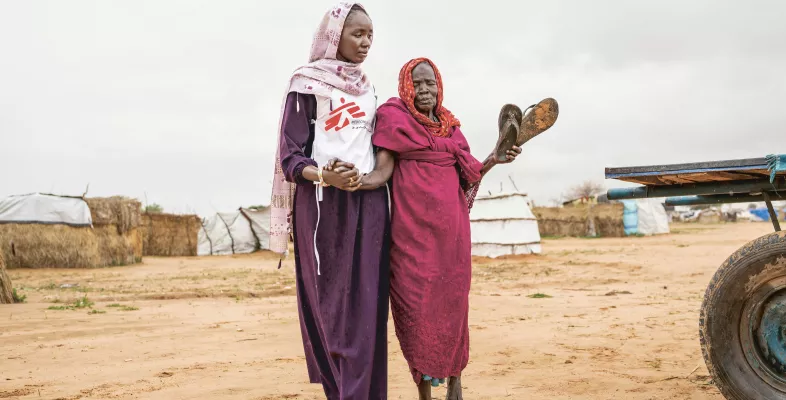 Eine Mitarbeiterin von Ärzte ohne Grenzen stützt eine 80-Jährige Patientin Eine Mitarbeiterin von Ärzte ohne Grenzen stützt eine 80-Jährige Patientin