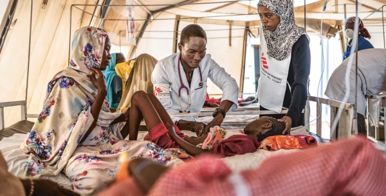 Arzt untersucht Kind - Mitarbeiterin übersetzt für Mutter