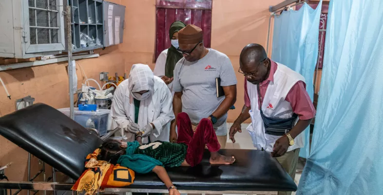 Kind lauf Behandlungsliege umgeben von Mitarbeitenden