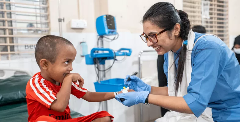 Ein kleiner Junge wird von einer Krankenschwester behandelt - beide lachen.