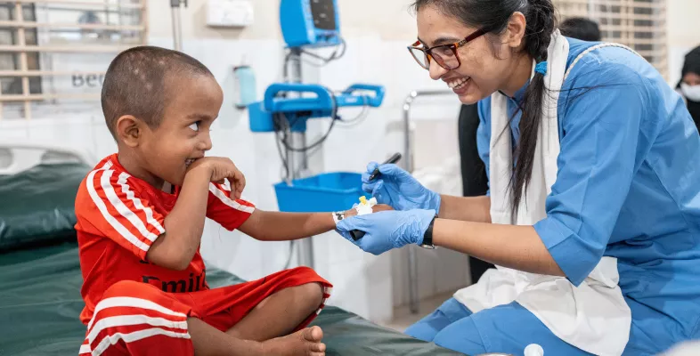 Ein kleiner Junge wird von einer Krankenschwester behandelt - beide lachen.