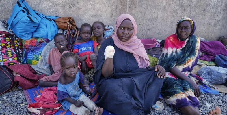 Frau zeigt amputierten Arm, daneben vier Kinder, eine Frau