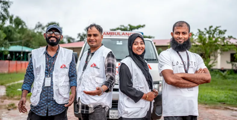 Vier lächelnde Mitarbeitende posieren vor Fahrzeug