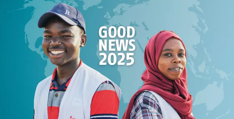 Zwei Personen stehen Rücken an Rücken und lächeln in die Kamera. Dahinter der Schriftzug "Good News".