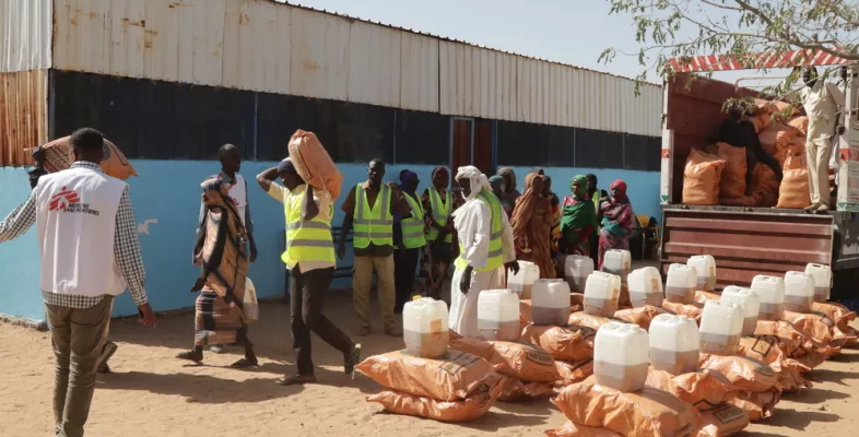 Mehrere Personen laden Säcke mit Nahrung ab und sortieren diese.