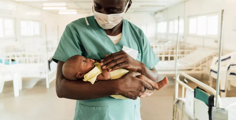 Ein Krankenpfleger in Sierra Leona hält ein Neugeborenes.
