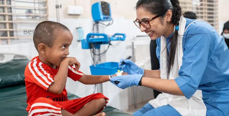 Ein kleiner Junge wird von einer Krankenschwester behandelt - beide lachen.