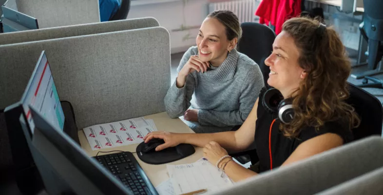 Zwei Mitarbeitende am Schreibtisch vor dem Computer