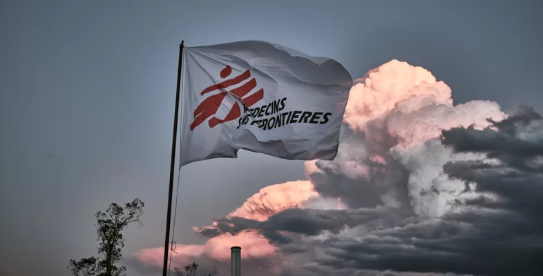 Flagge mit Logo von Ärzte ohne Grenzen vor bewölktem Himmel