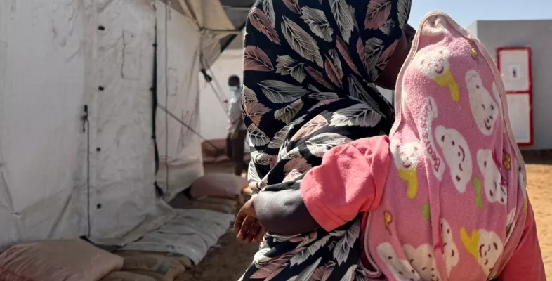 Frau mit Kopftuch hält Kind auf dem Arm