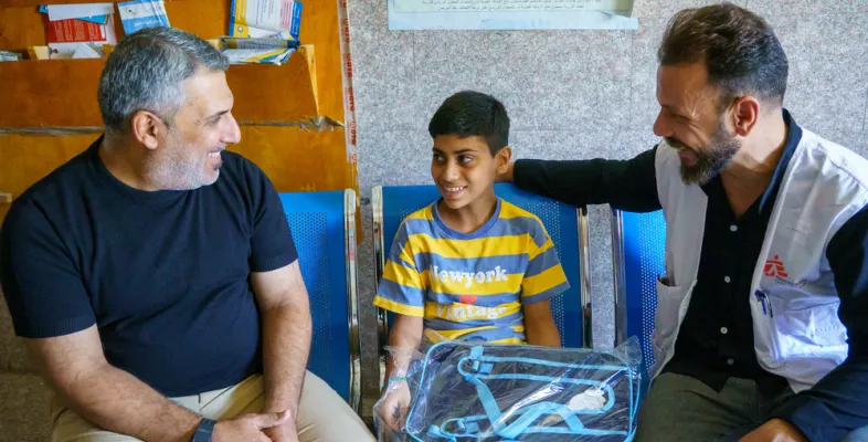 Junge sitzt zwischen seinem Vater und unserem Mitarbeitenden