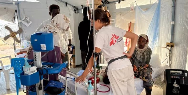 Mitarbeiterin und Angehörige an Bett von Kleinkind