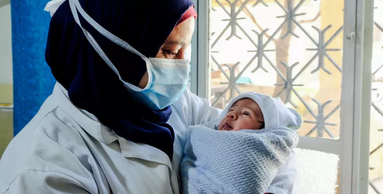 Hebamme hält Baby im Arm