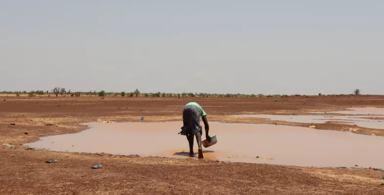 Person schöpft Regenwasser vom Boden