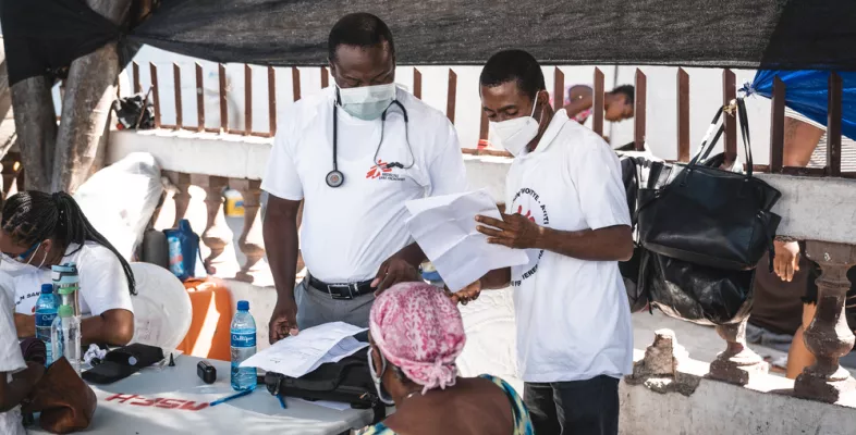 Zwei Ärzte sprechen mit einem Patienten in einem Camp für Vertriebene