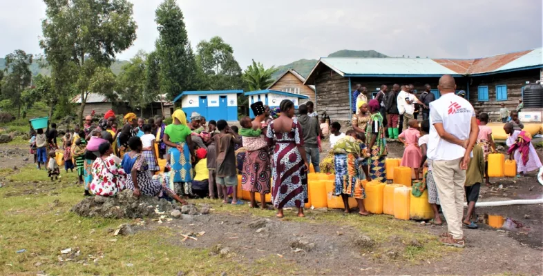Die Bewohner*innen der Geflüchtetenunterkunft warten darauf, ihre Kanister mit Trinkwasser zu füllen 