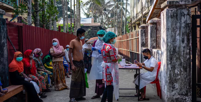 Patient*innen stehen am Eingang der mobilen Klinik in Aung Mingalar, Sittwe