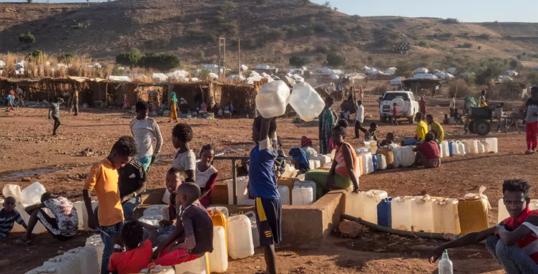 Menschen stehen mit Kanistern an einer Wasserversorgung an 