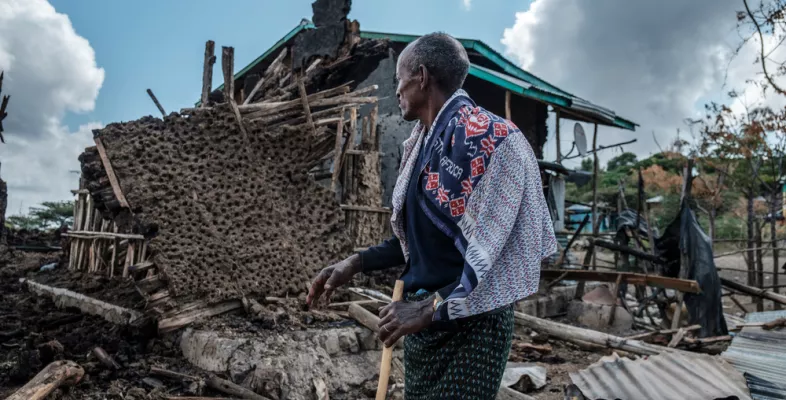 Person vor zerstörtem Haus