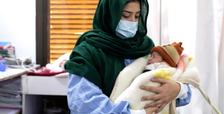 Eine Mitarbeiterin in Pakistan hält ein Neugeborenes auf ihrem Arm.