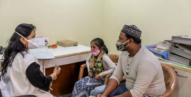 Eine Sozialarbeiterin von Ärzte ohne Grenzen im Gespräch zur Nachsorge mit einer Tuberkulose-Überlebenden und ihrem Vater. 