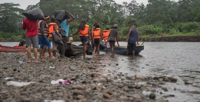 Menschen mit Rettungswesten steigen in ein Kanu auf einem Fluss ein