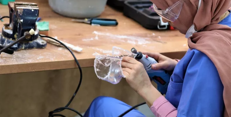 Eine Frau modelliert eine Kunststoffmaske mit einem Schleifgerät