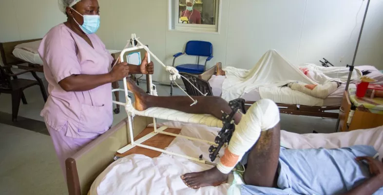 Eine Krankenpflegerin steht am Bett eines Patienten, der während des Erdbebens den Fuß gebrochen hat.