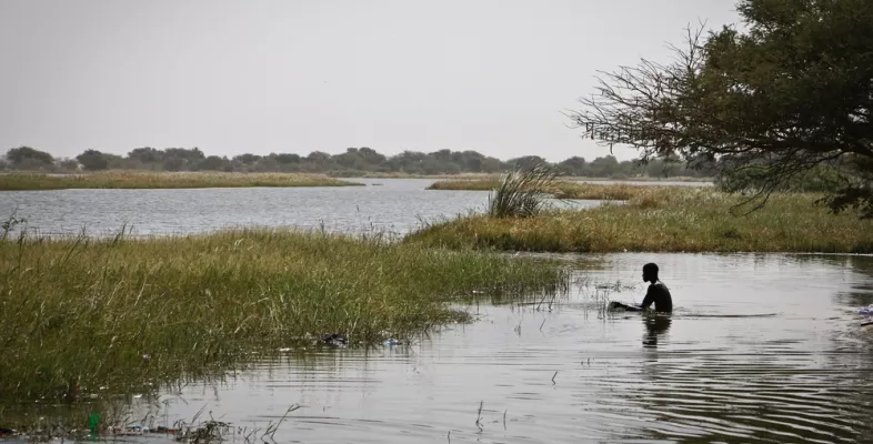 Mensch sitzt im Wasser am Ufer des Tschadsee