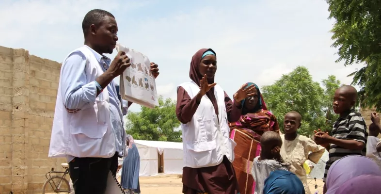Mitarbeiter*innen der Gesundheitsförderung sprechen mit Vertriebenen in einem Camp in Borno