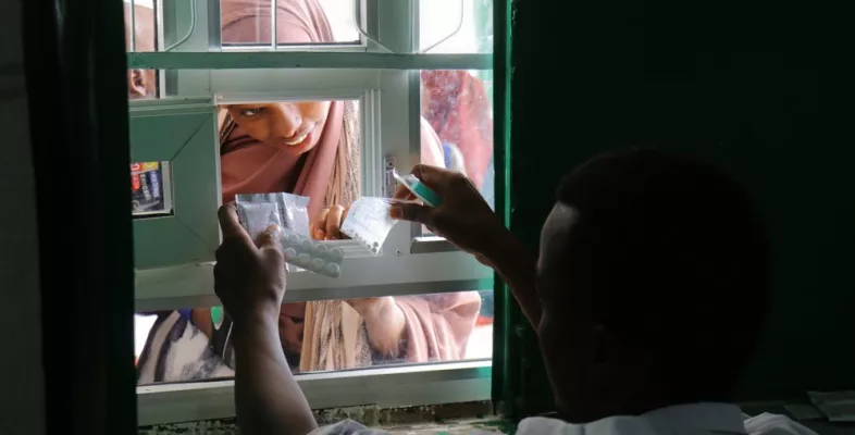 Eine Frau erhält ihre Medikamente durch ein Fenster.