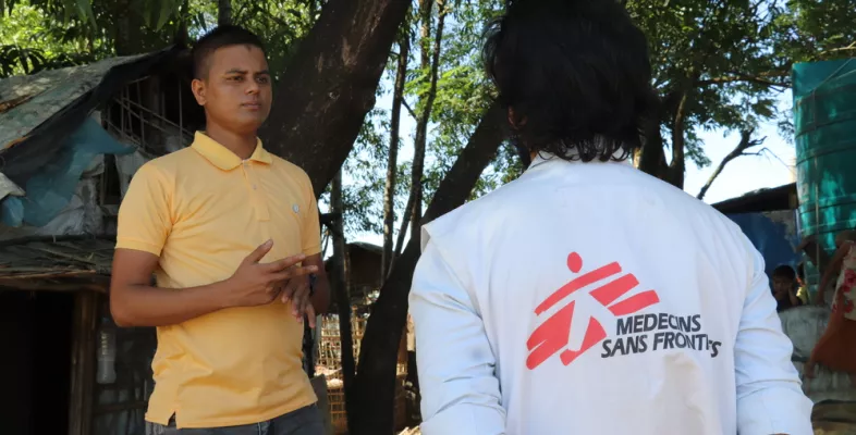 Mann in gelbem Polohemd spricht mit Mitarbeiter