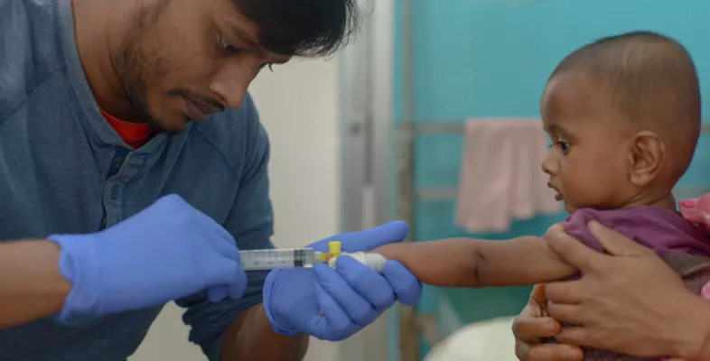 Ein Pfleger legt einen Zugang bei einem Kleinkind.