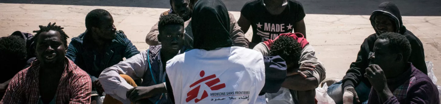 Eine Gruppe von Menschen sitzt auf dem Boden vor einem Gebäude