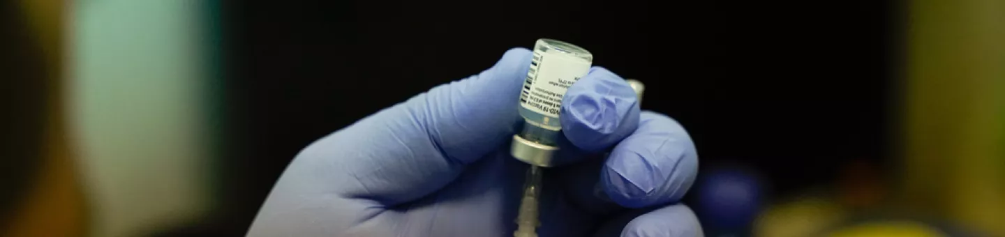 Impfstoff wird aus einer Ampulle in einer Spritze aufgezogen.