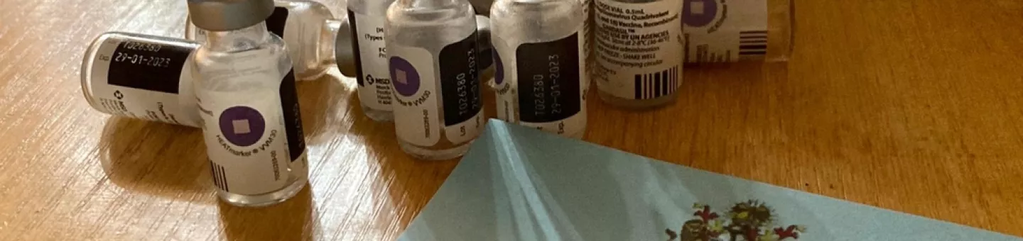 Auf einem Tisch stehen HPV Impfdosen und ein Impfzertifikat.