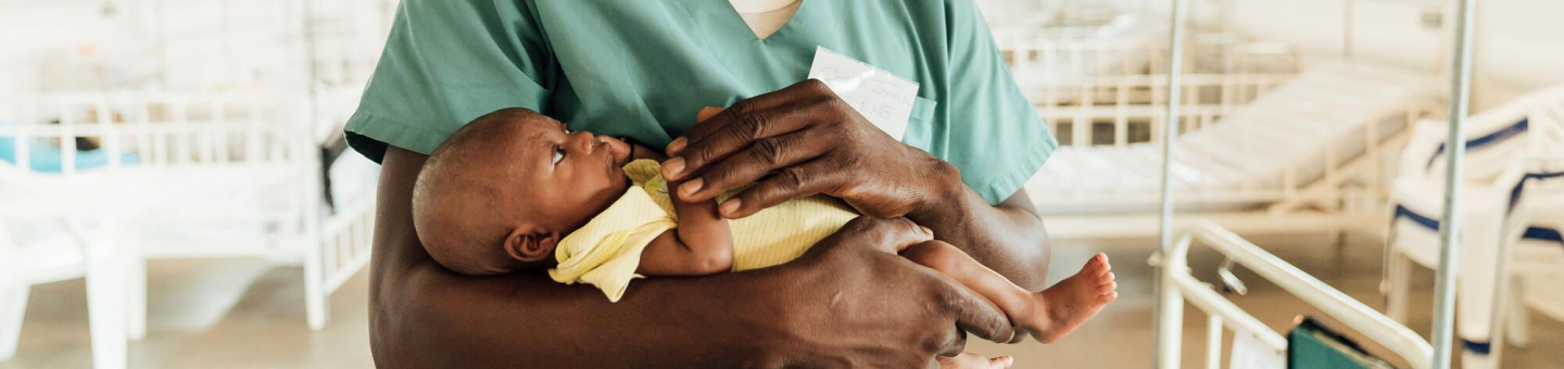 Ein Krankenpfleger in Sierra Leona hält ein Neugeborenes.