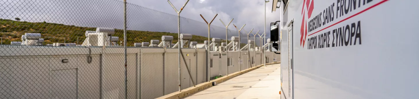 Mobiles Klinikfahrzeug von Ärzte ohne Grenzen innerhalb des geschlossenen Kontrollzentrums in Zervou, Samos. Mobiles Klinikfahrzeug von Ärzte ohne Grenzen in Zervou, Samos neben einem Stacheldrahtzaun