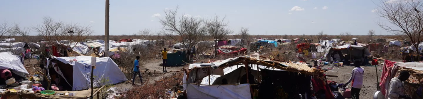 Ein Camp aus provisorischen Zeltunterkünften mit Menschen